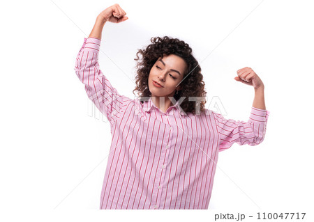 young cute curly-haired caucasian woman dressed in a striped pink blouse actively gesticulates with young cute curly-haired caucasian woman dressed in a striped pink blouse actively gesticulates with 110047717