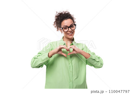 young brunette businesswoman with curly hair dressed in a green shirt wears eyeglasses young brunette businesswoman with curly hair dressed in a green shirt wears eyeglasses 110047797