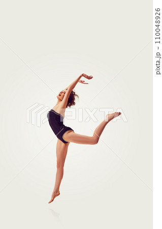 Beautiful, elegant, slim, young woman in stylish vintage swimsuit cheerfully jumping against white background Beautiful, elegant, slim, young woman in stylish vintage swimsuit cheerfully jumping against white background 110048926