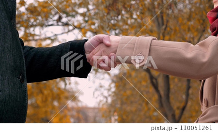 Man extends hand to woman as sign of agreement to maintain company at meeting Man extends hand to woman as sign of agreement to maintain company at meeting 110051261