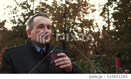 Man walks through city park to meeting with entrepreneur drinking hot coffee 110051265