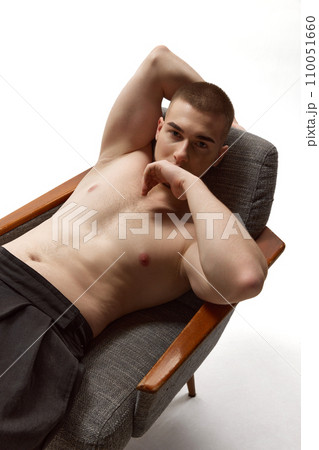 Full length aerial view portrait of young man covers face with hands leaving eyes and stares defiantly at camera against white background. Full length aerial view portrait of young man covers face with hands leaving eyes and stares defiantly at camera against white background. 110051660