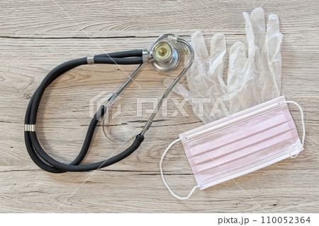 Surgical mask, stethoscope and medical gloves layed out on wooden background 110052364