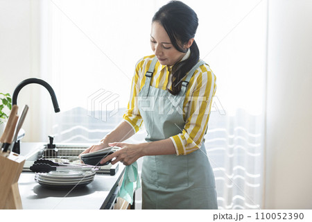 食器を洗うエプロン姿の女性 110052390