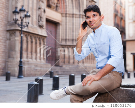 Modern guy walks in city and communicates on smartphone 110053176