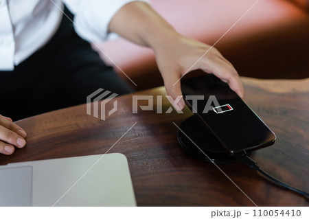 Hands of businessman putting smartphone on wireless charger device to charging battery mobile phone 110054410
