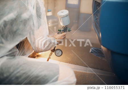 Car painter in protective clothes and respirator mask painting vehicle 110055371