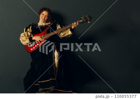 Portrait of a young adult woman playing rock music on electric guitar and dressed in a medieval dress Portrait of a young adult woman playing rock music on electric guitar and dressed in a medieval dress 110055377