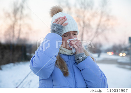 Close-up of a silhouette of a girl who is sick and puts a handkerchief to her nose. 110055997
