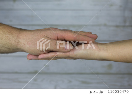Elderly man's hand lies on woman's aged hand on white background. Senior people relationship concept 110056470