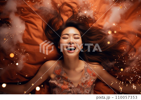 Young Asian woman having orgasm. Beautiful woman with open mouth and closed eyes enjoying sex lying among fireworks. Sparklers as a symbol of orgasm. Sexual experience, masturbation, cunnilingus. 110057353