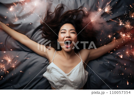 Young Asian woman having orgasm. Beautiful woman with open mouth and closed eyes enjoying sex lying among fireworks. Sparklers as a symbol of orgasm. Sexual experience, masturbation, cunnilingus. Young Asian woman having orgasm. Beautiful woman with open mouth and closed eyes enjoying sex lying among fireworks. Sparklers as a symbol of orgasm. Sexual experience, masturbation, cunnilingus. 110057354