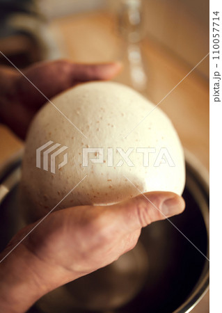 Close up shot of baker holding white and slightly sticky pastry made from environmentally friendly ingredients. 110057714