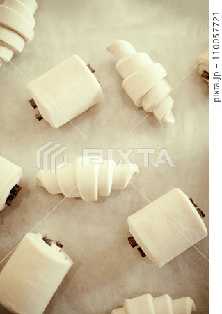 Close up top view photo of pastries, croissants and bread with bars of chocolate sitting on baking tray covered with parchment. Concept of recipes, traditions. Close up top view photo of pastries, croissants and bread with bars of chocolate sitting on baking tray covered with parchment. Concept of recipes, traditions. 110057721