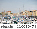 Motor and sailboats are tightly parked in the marina of Marseille against the backdrop of the city. 110059474