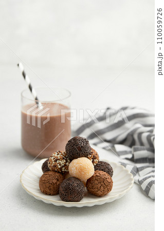 Typical Brazilian sweet brigadeiro. A heap of assorted flavors of candies on a white table 110059726