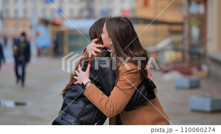 Two best friends meet on the streets of the city and hug. 110060274