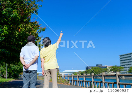 ウォーキング中に青空を指差しするアクティブシニアの男女夫婦　ダイエット　運動目標　健康習慣　朝カラー 110060987
