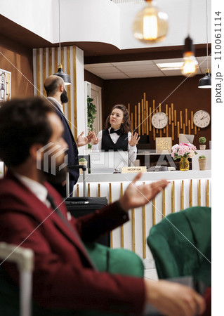 Employee greeting businessman, providing good recommendations to ensure pleasant work stay. Business traveller asking about hotel room services at resort, impeccable customer service. 110061114