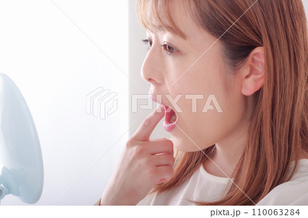 鏡で口内を確認している若い女性 110063284