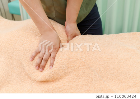 腰の症状、腰痛の患者と診察や手技を行う整体師やマッサージ師イメージ。手のクローズアップ 110063424