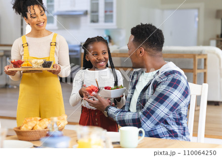 Happy african american family bringing fresh fruits on table in dining room at home, copy space Happy african american family bringing fresh fruits on table in dining room at home, copy space 110064250