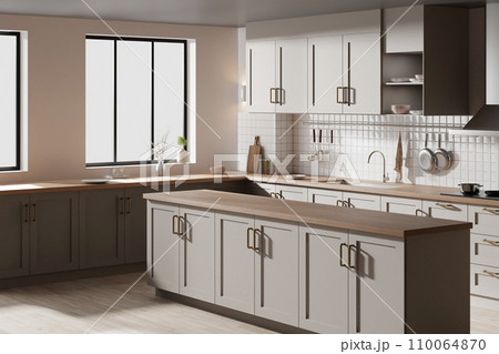 A bright beige-toned kitchen interior with sunlight coming through the window. 110064870