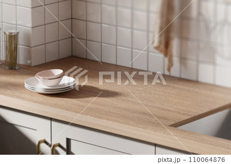 A bright beige-toned kitchen interior with sunlight coming through the window. A bright beige-toned kitchen interior with sunlight coming through the window. 110064876