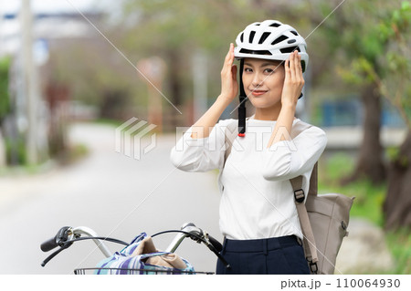 サイクリングヘルメットを被って手で抑える若い女性 サイクリングヘルメットを被って手で抑える若い女性 110064930