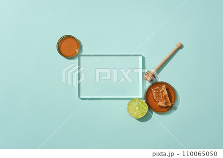 A glass platform is placed in the center of the frame, next to a bee face in a petri dish and fresh lemon. Empty podium for product display. Green background for advertising. A glass platform is placed in the center of the frame, next to a bee face in a petri dish and fresh lemon. Empty podium for product display. Green background for advertising. 110065050