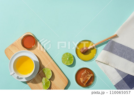 A cup of tea with main ingredients from lemon and honey is placed on a wooden tray. Blank space for design. Use honey tea to improve health condition. A cup of tea with main ingredients from lemon and honey is placed on a wooden tray. Blank space for design. Use honey tea to improve health condition. 110065057