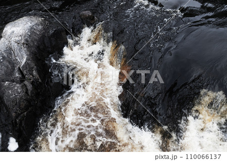 Fast water with foam goes over black rocks. Waterfalls of Ruskeala 110066137