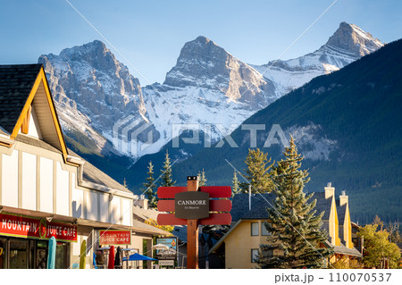 Canmore, AB, Canada - Oct 7 2023 : Canmore Town Sign. The Three Sisters trio of peaks over the blue sky in the background. Canmore, AB, Canada - Oct 7 2023 : Canmore Town Sign. The Three Sisters trio of peaks over the blue sky in the background. 110070537