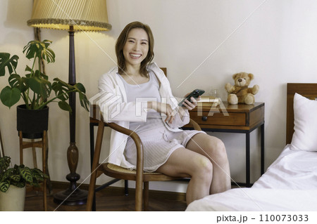 自宅のデスク前に座ってスマホを操作する茶髪の若い女性のポートレート 自宅のデスク前に座ってスマホを操作する茶髪の若い女性のポートレート 110073033