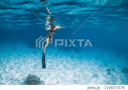 Woman with fins swimming over sandy sea. Free diver in blue ocean in Hawaii 110073376
