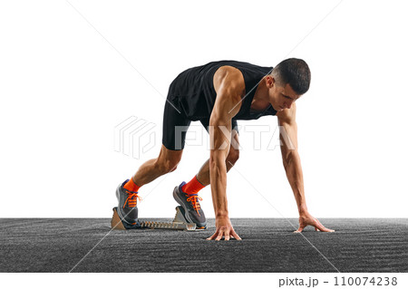 Young athletic man, professional jogger preparing to run while standing at low start against white pristine background. Young athletic man, professional jogger preparing to run while standing at low start against white pristine background. 110074238