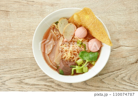 Chinese yellow egg noodles with fish ball and chop pork in red soup on bowl 110074787