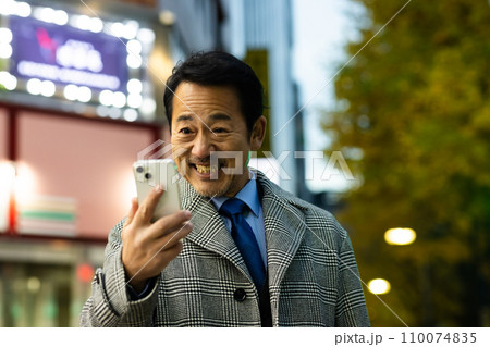 会社帰りにスマホをチェックするビジネスマン 会社帰りにスマホをチェックするビジネスマン 110074835