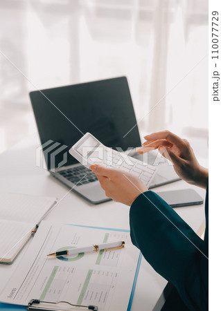 Businessman using a calculator to calculate numbers on a company's financial documents, he is analyzing historical financial data to plan how to grow the company. Financial concept. 110077729