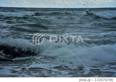 rocky seashore, surf and waves are broken by splashes and foam 110078706