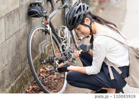 ロードバイクに 携帯用ポンプで空気を入れている若い女性 ロードバイクに 携帯用ポンプで空気を入れている若い女性 110083919