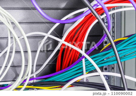 bunch of patch network cables sorted in rack cabinet, leading from patch panel in the server rack in the data center room 110090002