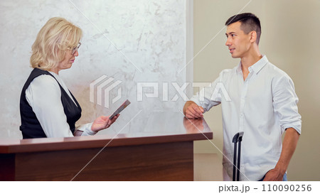 Young man handing over passport to find reserved hotel room 110090256