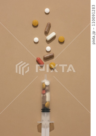 The pills are contained in a syringe on a brown background. The medicine has curative and inhibitory effects to limit the severity of the disease. The pills are contained in a syringe on a brown background. The medicine has curative and inhibitory effects to limit the severity of the disease. 110091283