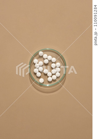 The round white pills are displayed on a transparent petri dish on a brown background. Antibiotics with bactericidal activity may improve bacterial killing. 110091284