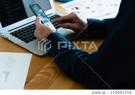 パソコンとスマホを操作する男性の手元 110091358