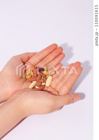Two hands together holding colorful pills on white background. Medicines used to treat diseases. Drug concept for advertising and other purposes. 110091615