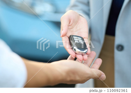 外で車の鍵を渡す女性 110092361