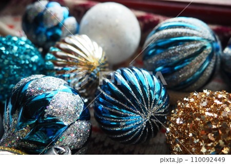 New Year's Christmas balls and decorations close up. A lot of decoration of golden, blue, yellow, white, silver. Striped Christmas balls lie on surface. Festive beautiful colorful background. Design. 110092449