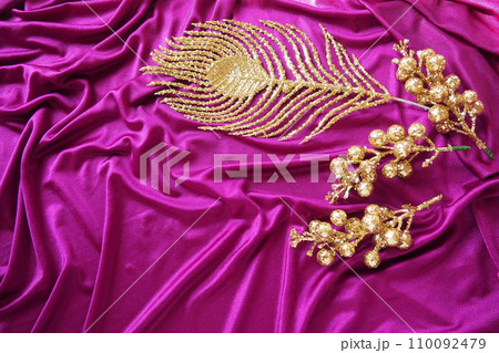 Purple pink lilac violet silk fabric texture background. Beautiful folds on the twisted material. Golden New Year Christmas decorations, Firebird feather, berries and twigs. Copy space. Xmas design Purple pink lilac violet silk fabric texture background. Beautiful folds on the twisted material. Golden New Year Christmas decorations, Firebird feather, berries and twigs. Copy space. Xmas design 110092479